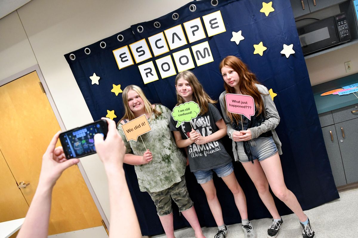 Gina Frerichs, a youth services librarian with Spokane Libraries snaps a photo of friends Madelyn Brown, 14, left, Betty Perrey, 15, center, and Kaley Graupman, 14, Kaley Graupman, 14, after they solved an escape room on Tuesday, June 25, 2019, at Hillyard Library in Spokane, Wash. (Tyler Tjomsland / The Spokesman-Review)