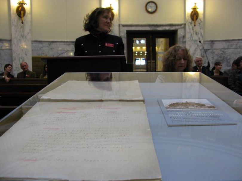 Idaho Historical Society Director Janet Gallimore concludes her budget presentation to the Joint Finance-Appropriations Committee on Thursday by displaying the original Idaho Constitution, in a glass case, to lawmakers. It was signed by 62 members of Idaho's Constitutional Convention on Aug. 6, 1889. (Betsy Russell)