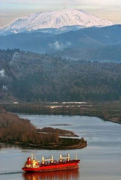 With Mount St. Helens shown in the distance, a cargo ship moves upriver on the Columbia River near the Cowlitz River. (Associated Press)