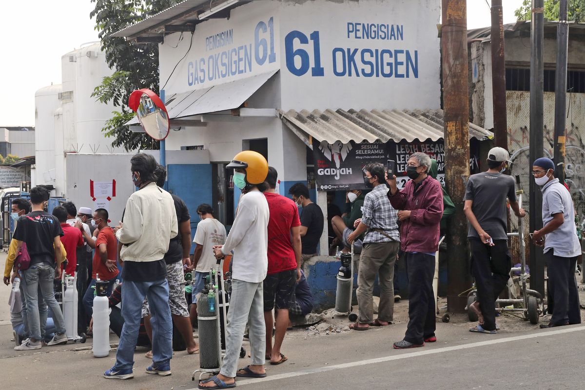 People wait for their turn to refill their oxygen tanks at a recharging station in Jakarta, Indonesia, Friday, July 9, 2021. Just two months ago, Indonesia was coming to a gasping India