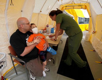 Brad Gibbons holds his son Daniel, 5, as nurse Torrey Jones asks questions Friday  in a tent in front of Arrowhead Regional Medical Center in Colton, Calif., set up to treat patients with flu symptoms.  (Associated Press / The Spokesman-Review)