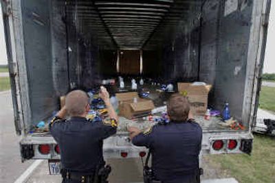 
Two Fort Worth police officers examine the trailer of a truck that was seized Sunday after 79 illegal immigrants were found hiding inside it during a traffic stop on Interstate 20 in Fort Worth. 
 (Associated Press photos / The Spokesman-Review)