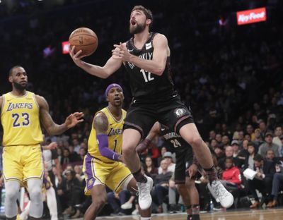 Brooklyn Nets' Joe Harris (12) drives past Los Angeles Lakers' LeBron James (23) during Tuesday’s game. Brooklyn won 115-110. (Frank Franklin II / Associated Press)