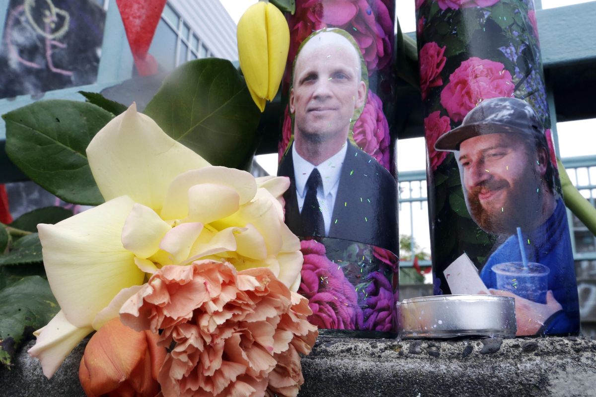 In this Wednesday, May 31, 2017, photo, candles with photos of Taliesin Namkai-Meche, right, and Ricky Best on them sit at a memorial for the two men in Portland. Jeremy Christian is accused of stabbing the two men to death while they tried to stop him from hurling anti-Muslim insults at young women on a Portland light rail train May 26, 2017. (Don Ryan / Associated Press)