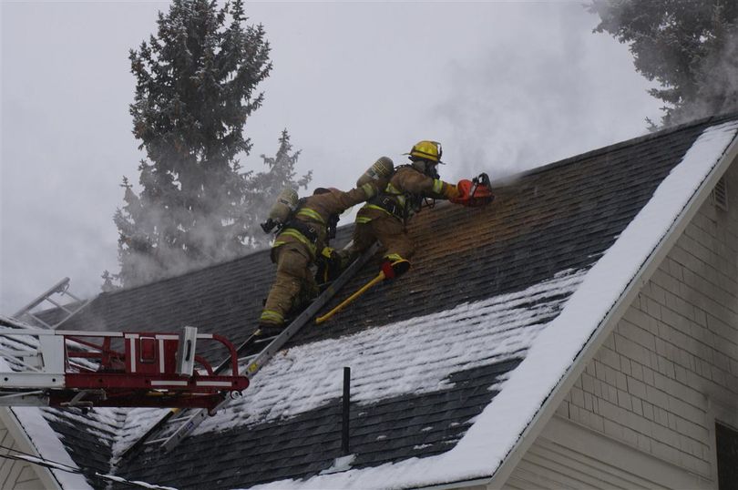 Firefighters balance on a roof as they cut into it while fighting a fire at 21023 E. Wellesley on Jan. 28, 2103.  (Photo courtesy the Spokane Valley Fire Department)
