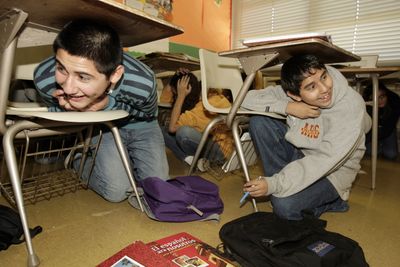 Anthony Lopez, 15, left, Ruben Tarango, 15, and other students at Bishop Alemany High  duck under their desks during an earthquake drill  Nov. 13 in the Mission Hills section of Los Angeles. (Associated Press / The Spokesman-Review)