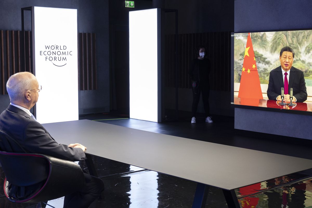 German Klaus Schwab, left, Founder and Executive Chairman of the World Economic Forum (WEF), listens to Chinese President Xi Jinping displayed in a screen during a the opening Davos Agenda 2022, in Cologny near Geneva, Switzerland, Monday, Jan. 17, 2022. The Davos Agenda, from 17 to 21 January 2022, is an online edition due to the coronavirus disease (COVID-19) outbreak gather global leaders to shape the principles, policies and partnerships needed in this challenging context.]/Keystone via AP)  (Salvatore di Nolfi)
