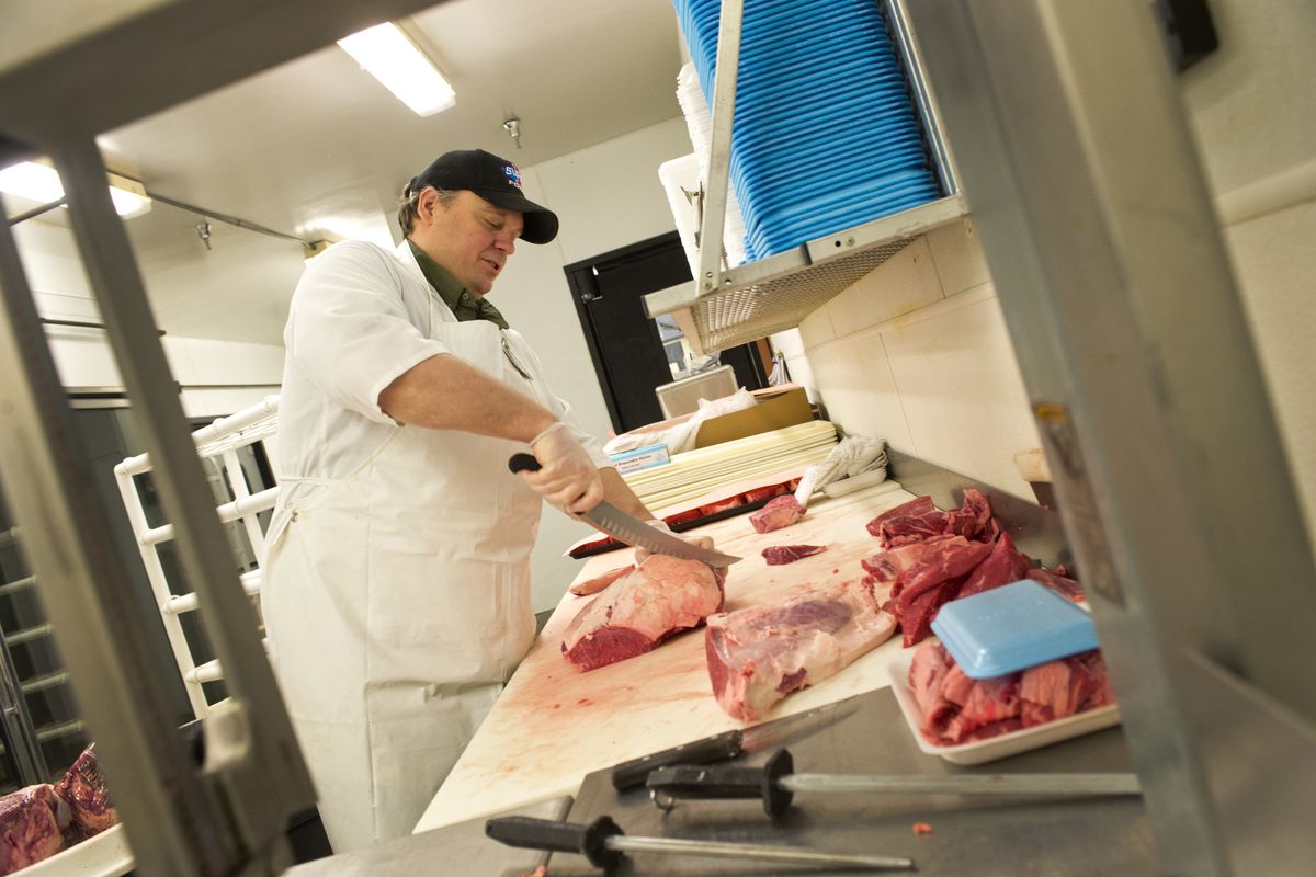 Meat cutter Derrick Self deftly turns a large sirloin into steaks in the meat department of the Super 1 Foods on 29th Avenue in Spokane on Monday. He has worked there for 22 years. (Jesse Tinsley)