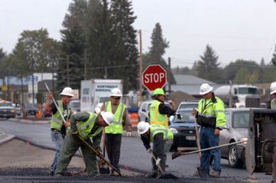 
One-way traffic inches around workers spreading asphalt Thursday on Government Way in Hayden. The construction has hurt businesses, but is expected to be finished by Oct. 24.  
 (Jesse Tinsley / The Spokesman-Review)