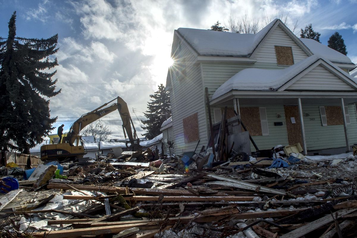 A bulldozer operator steps toward the cab to continue cleanup of this nuisance home in Spokane