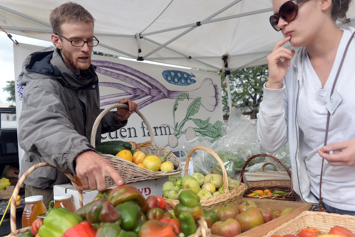 Farmer Patrick Mannhard, left, helps customer Britta Howard choose from among a selection of peppers at the Urban Eden Farm stand at the Spokane Farmers Market on Wednesday. Mannhard said he favors mandatory labeling of genetically modified foods. (Jesse Tinsley)