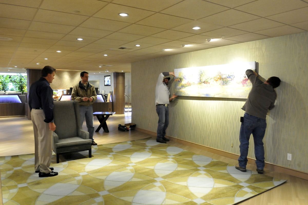 Designer Guy Dreier, far left, watches as workmen lay carpet and hang paintings in the lobby of the Coeur d