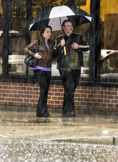 Sudden deluge: During a sudden thunderstorm Wednesday, Adam and Jennifer Sharp head south on Post Street in downtown Spokane. The storm caused numerous power surges and outages throughout the region. (Colin Mulvany)