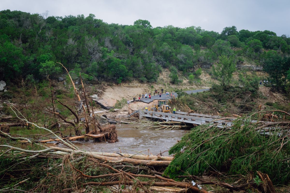 Construction crews clear flood debris in Ingram, Texas, for residents to cross a bridge over the Guadalupe River on July 5. (Desiree Rios/For The Washington Post)