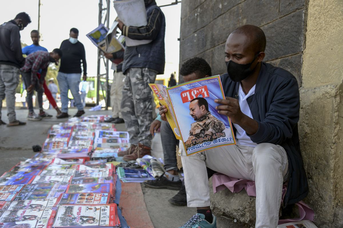 Ethiopians read newspapers and magazines reporting on the current military confrontation in the country, one of which shows a photograph of Prime Minister Abiy Ahmed, on a street in the capital Addis Ababa, Ethiopia Saturday, Nov. 7, 2020. Ethiopia moved Saturday to replace the leadership of the country
