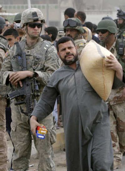 U.S. and Iraqi soldiers distribute food and humanitarian supplies  in Sadr City,  Baghdad, on Friday. Sadr City is lacking basic supplies as a result of a curfew  set on the district after last week's violence. Associated Press
 (Associated Press / The Spokesman-Review)