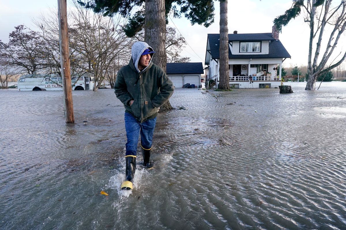 Benjamin Lopez steps from floodwater surrounding his parents home Monday in Sedro-Woolley, Wash.  (Elaine Thompson)