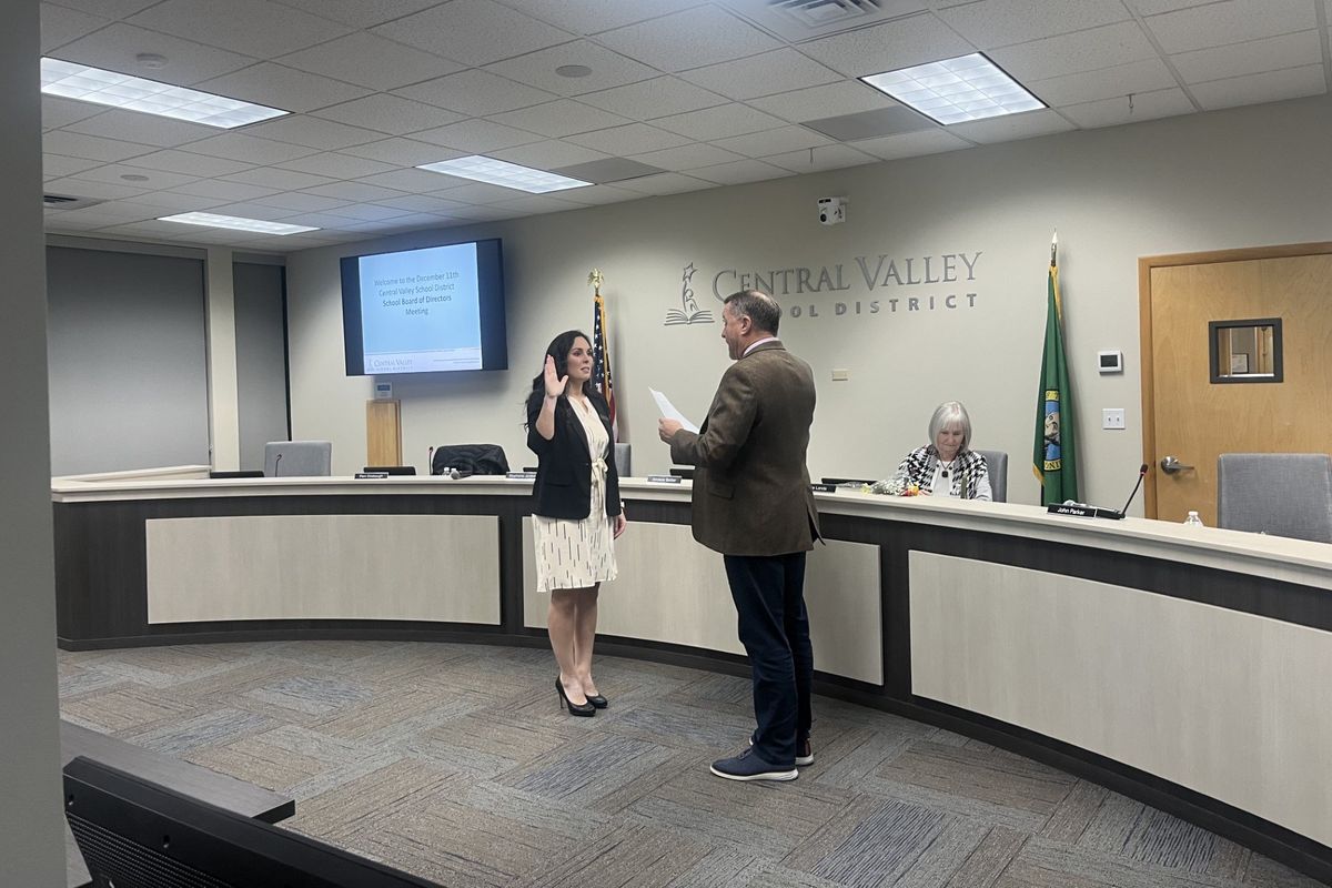 Superintendent John Parker leads new-to-office Anniece Barker in reciting her oath of office at Monday’s school board meeting.  (Elena Perry)