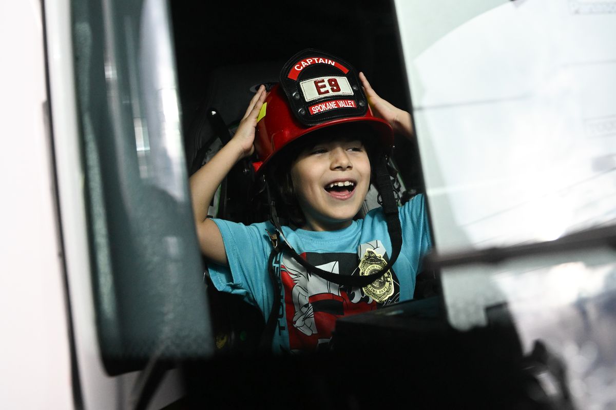 Leonel Bermudez, 8, is photographed through the windshield of Engine 9 as he tries on Spokane Valley Fire Station 9 Captain Josh Loftin’s helmet after Bermudez received a Lifesaving award on Wednesday, Dec. 20, 2023, in Spokane Valley, Wash. Bermudez recieved the award for saving his mother’s life after she had a seizure and Bermudez called 911 and Captain Loftin and his crew responded. (Tyler Tjomsland/The Spokesman-Review)