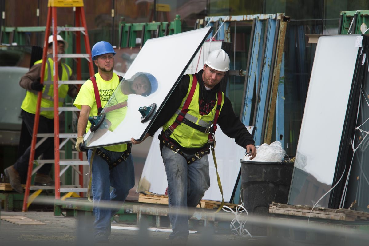 Jacob Williams, left, and Anthony Pendergraft, of Skaug Brothers Glass, carry windows for placement on the building Monday.