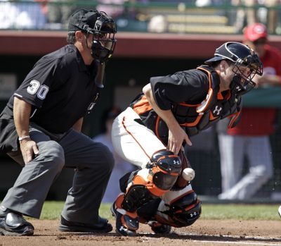 Giants catcher Buster Posey digs out a pitch in the dirt while home-plate umpire Rob Drake looks on. (Associated Press)