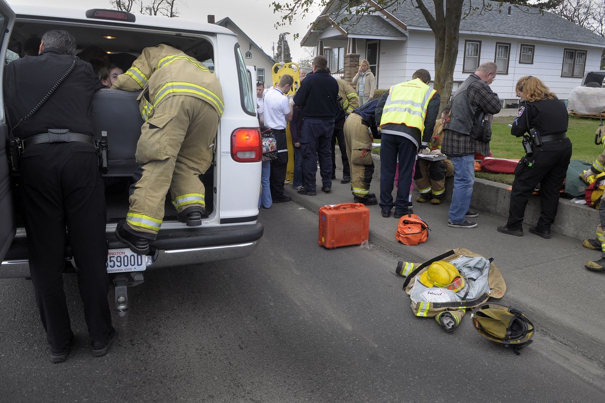 Spokane fire and police personnel work to free kids from a two-vehicle accident at Wellesley Avenue at Cook Street on April 23, 2009.  The vans were filled with children from a before-school program headed to Regal and Logan elementaries.   The large number of passengers required a two alarm response from the Fire department and every AMR ambulance available.  (Christopher Anderson / The Spokesman-Review)
