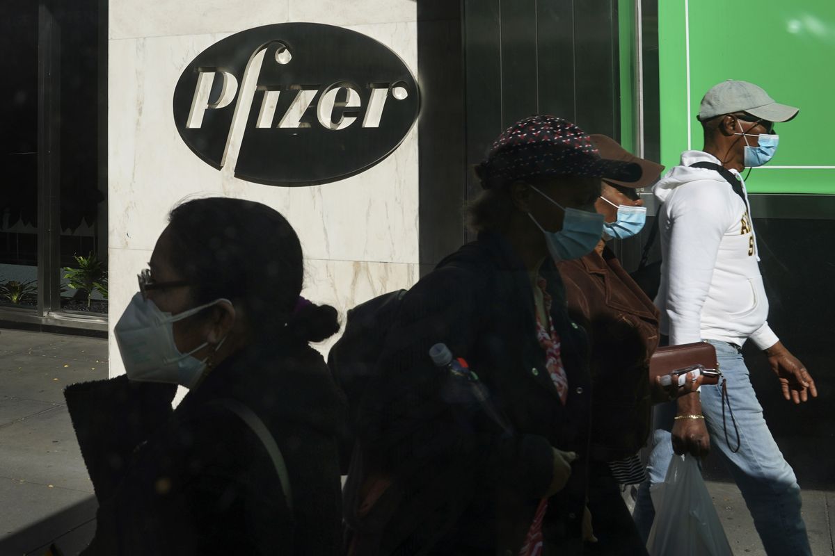 FILE - In this Nov. 9, 2020, file photo, pedestrians walk past Pfizer world headquarters in New York. A U.S. government advisory panel convened on Thursday, Dec. 10, to decide whether to endorse mass use of Pfizer