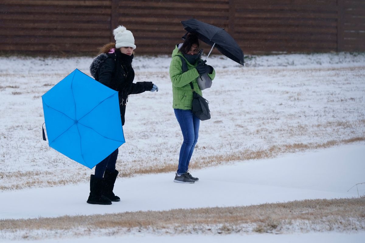 Amanda, left, and Rebecka try to use umbrellas as they walk to work during a light freezing rain Thursday in Dallas. A major winter storm with millions of Americans in its path is spreading rain, freezing rain and heavy snow further across the country.  (LM Otero/Associated Press)