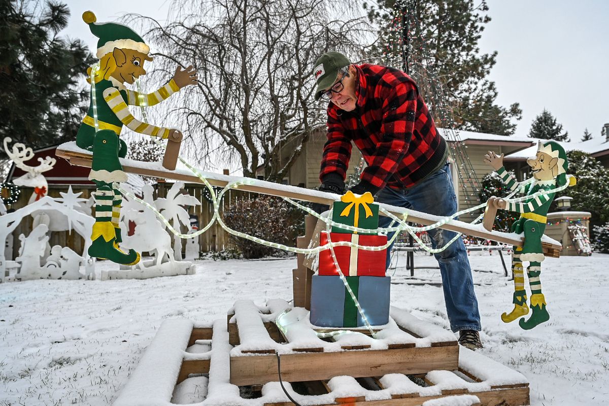 Jerry Schmidt works on a malfunctioning motor for his front-yard elf teeter-totter after a Friday morning snowfall covered the area near the corner of 39th Avenue and Havana Street.  (DAN PELLE/THE SPOKESMAN-REVIEW)