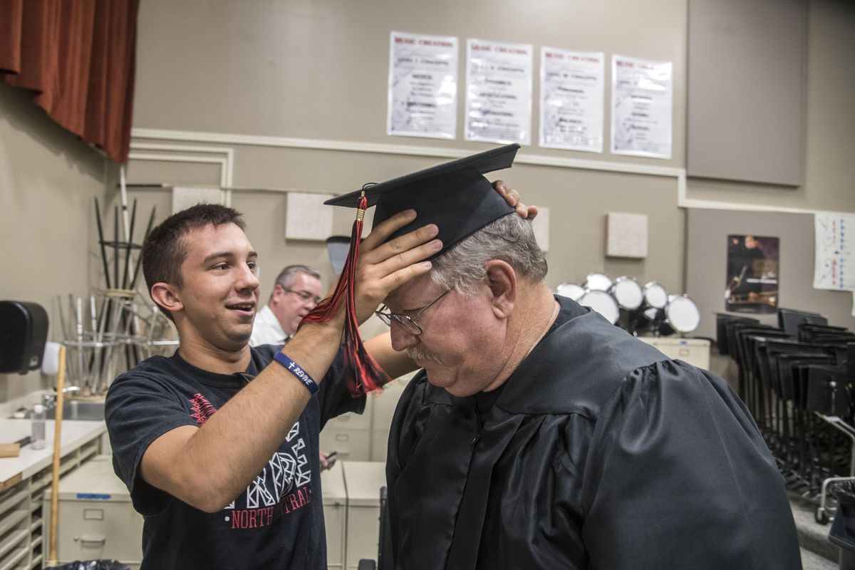 Frank Fuchs, North Central High School ASB president from last year, helps Stephen Rieckers fit his graduation cap before Rieckers received his honorary diploma, July 19, 2017. (Dan Pelle / The Spokesman-Review)