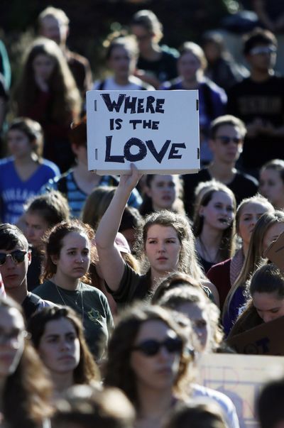 A South Eugene High School student holds signs during a march demonstrating for peace, harmony and unity after the highly divisive 2016 presidential election Wednesday in Eugene, Ore. (Andy Nelson / Andy Nelson Register-Guard)