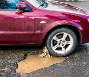 A car hits a pothole on Freya near Hartson in Spokane recently. (Dan Pelle/SR file photo)