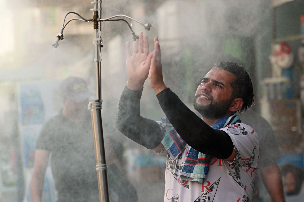 A man cools off from the summer heat under an open air shower in Baghdad, Iraq, Sunday, July 5, 2020. (Hadi Mizban)