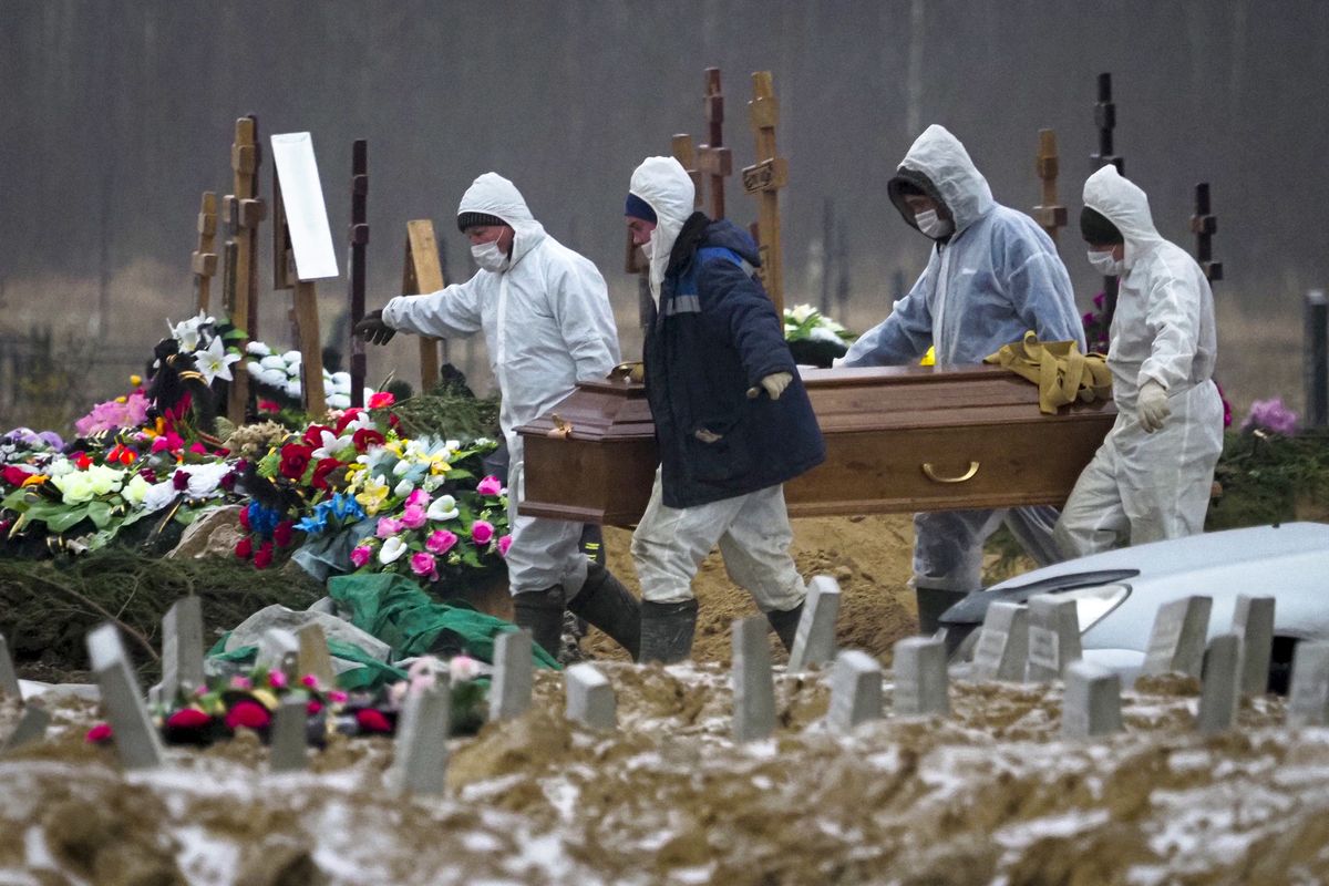 FILE In this file photo taken on Tuesday, Dec. 15, 2020, Grave diggers wearing protective suits carry the coffin of a COVID-19 victim in the section of a cemetery reserved for coronavirus victims in Kolpino, outside St.Petersburg, Russia. Russia's updated statistics on coronavirus-linked deaths showed that over 100,000 people with COVID-19 had died in the pandemic by December, a number much higher than previously reported by government officials. According to the data released Monday by Russia's state statistics agency, Rosstat, a total of 116,030 people with COVID-19 died in Russia between April and November. The count included cases where the virus was not the main cause of death and where the virus was suspected but not confirmed.  (Dmitri Lovetsky)