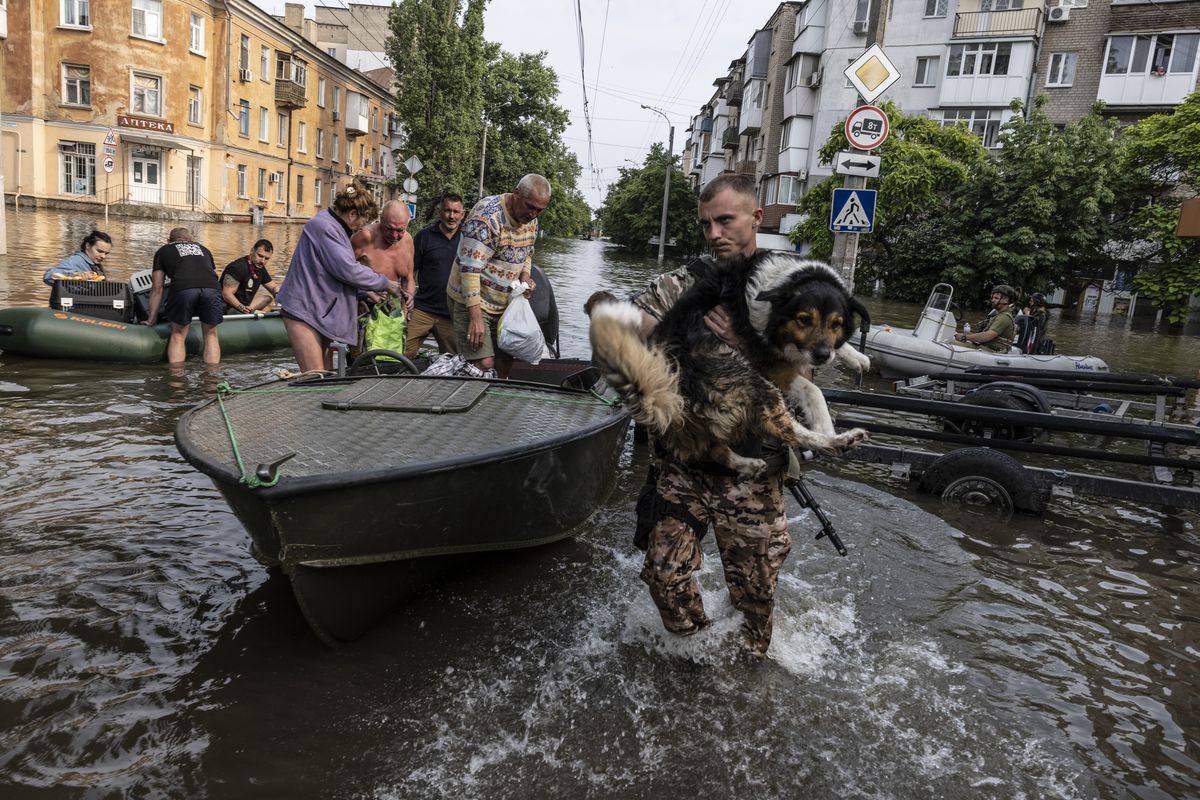 A Ukrainian soldier carries a pet dog through flooded Kherson city on Wednesday as residents evacuate their homes. MUST CREDIT: Photo for The Washington Post by Heidi Levine  (Heidi Levine/For The Washington Post)