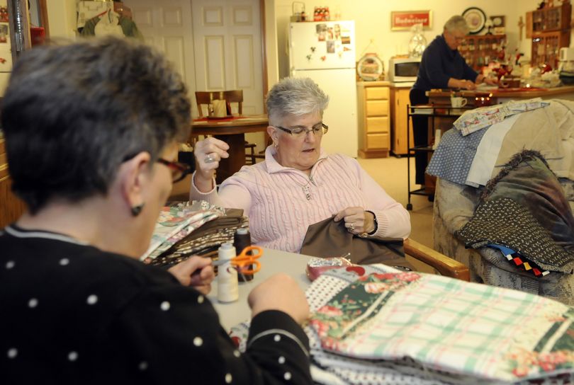 Betsy Blake, Cathy Lobe, center, and Jan Stripes, rear, work on producing homemade placemats for Meals on Wheels at Lobe’s home in northwest Spokane on Feb. 1. Below, a tag is attached to each placemat. (Dan Pelle)