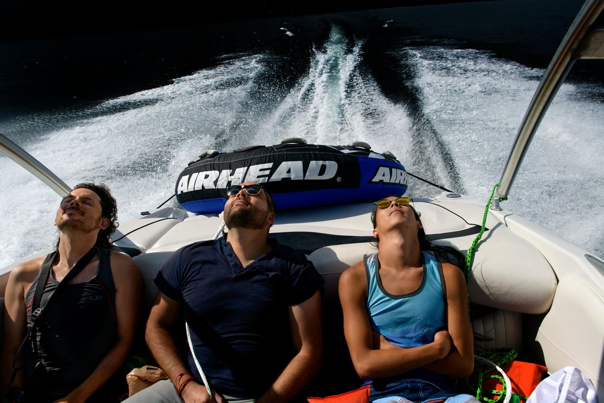From left, Andrew Holman, of Anchorage, AK, Rajah Bose of Spokane and Kai-Huei Yau of Seattle soak in the late afternoon sun while on a boat ride on Saturday, August 10, 2019, at Priest Lake near Coolin, ID. (Tyler Tjomsland / The Spokesman-Review)