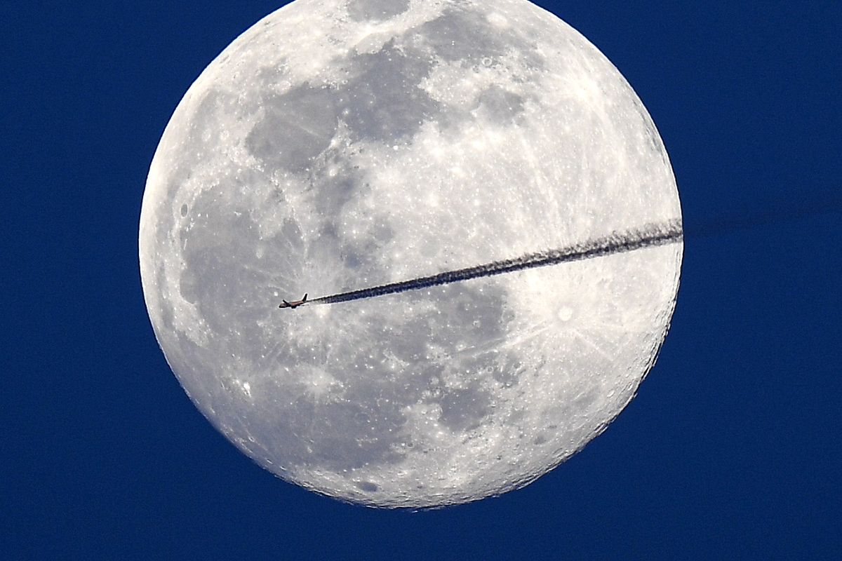 A jet flies northbound as the nearly full moon rises over Washington, D.C.  (Jonathan Newton/The Washington Post)