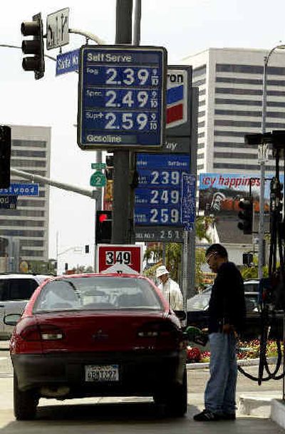 
A driver fills up his car as high gas prices are posted at two competing gas stations in the Westwood section of Los Angeles Tuesday.
 (Associated Press photos / The Spokesman-Review)