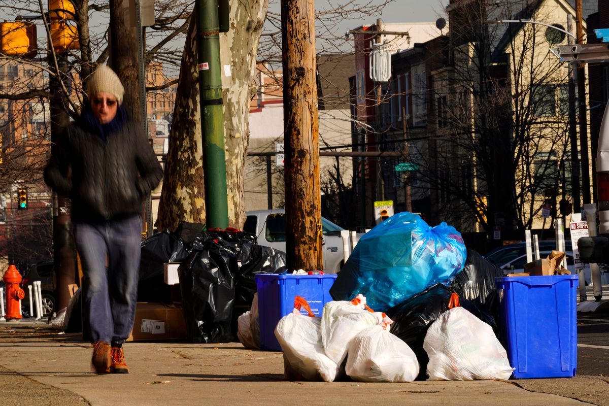 Trash sits out for collection in Philadelphia, Thursday, Jan. 13, 2022. The omicron variant is sickening so many sanitation workers around the U.S. that waste collection in Philadelphia and other cities has been delayed or suspended.  (Matt Rourke)