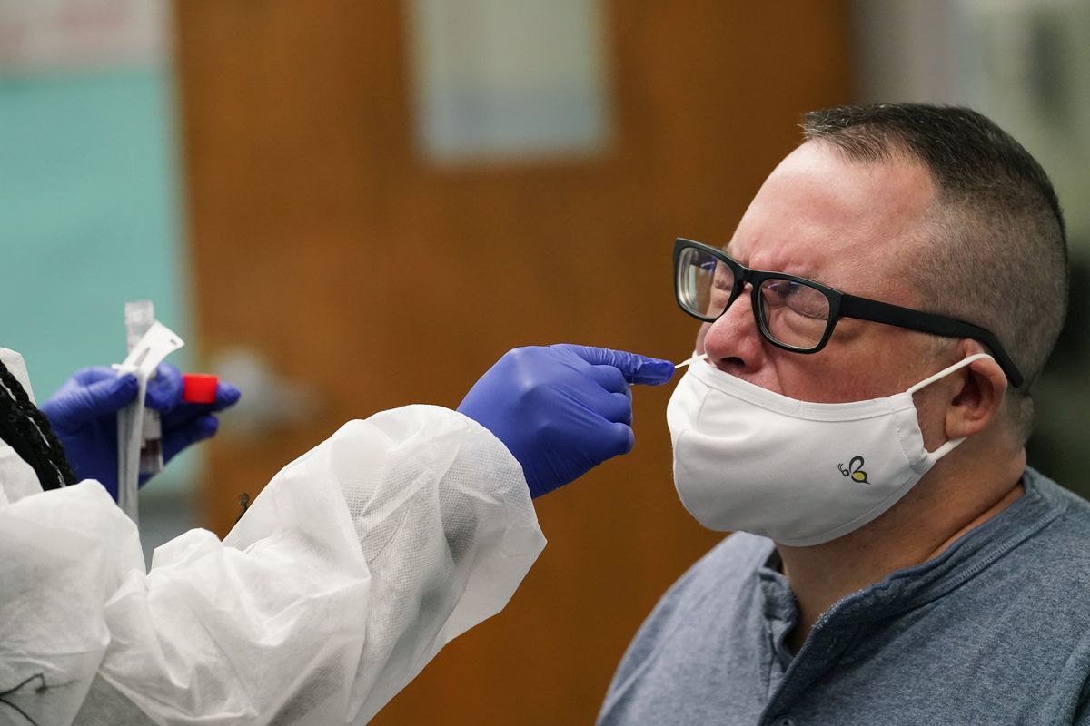 FILE - In this Oct. 29, 2020, file photo, English language arts teacher Frank Esposito submits to a COVID-19 nasal swab test at West Brooklyn Community High School in New York. New York City will require all of its municipal workers — including teachers and police officers — to get coronavirus vaccines by mid-September or face weekly COVID-19 testing, Mayor Bill de Blasio announced Monday, July 26, 2021.  (Kathy Willens)