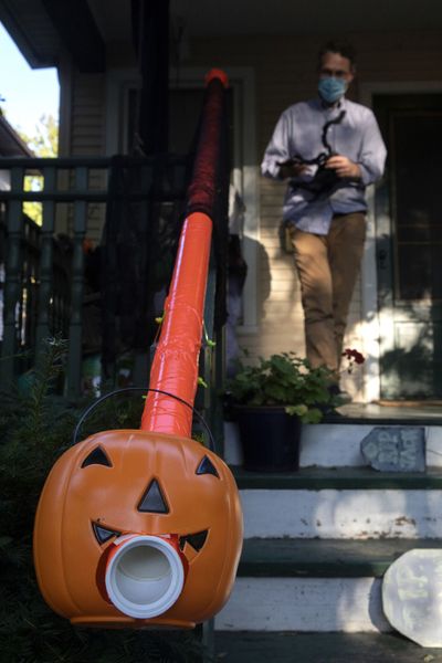 Liam Ford decorates his porch and Halloween treat chute. He was able to use pipe he found in his garage, plus orange duct tape and zip ties to create a candy-delivery system that allows for social distancing.  (Erin Hooley/Chicago Tribune)