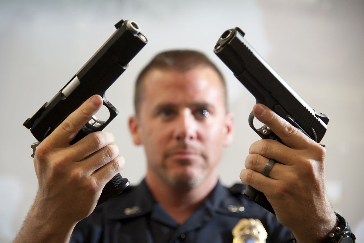 Spokane police Range Master Sgt. Chris Crane holds similar-looking handguns. A SOCOM Black Ops Airsoft Gun is at left and a Kimber .45 ACP pistol at right. The proliferation of weapons that appear genuine is a major worry for local law enforcement. (Dan Pelle)