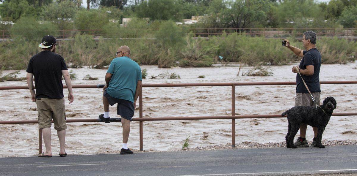 FILE — In this July 23, 2021 file photo, passersby watch the Rillito River rolling along just west of Swan Road after a powerful storm with heavy rain landed over the Tucson area, Ariz. After two bone-dry years that sank the U.S. Southwest deeper into drought, this summer