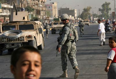 
U.S. soldiers run toward their armored vehicles after inspecting the site of a car bomb  blast Wednesday. Two bombs exploded  in north Baghdad killing at least nine people and wounding 39.
 (Associated Press / The Spokesman-Review)