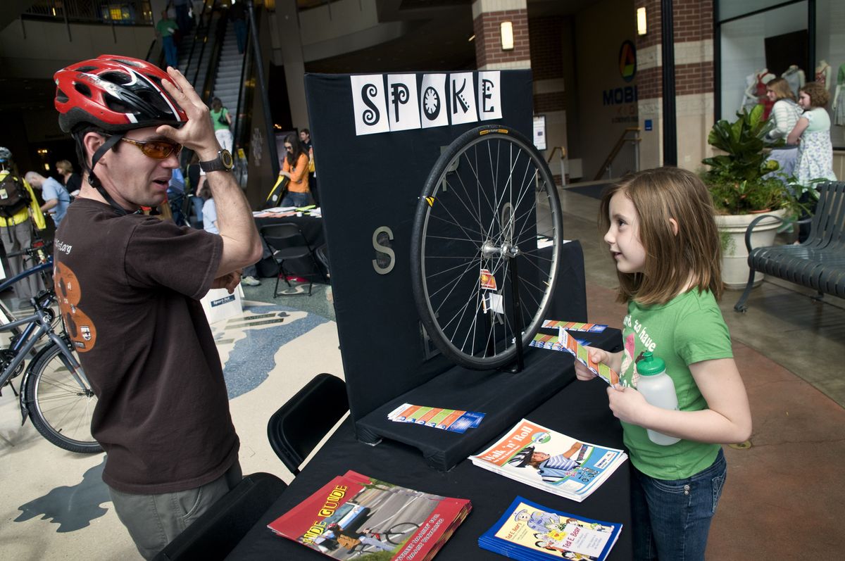 Daniel Henry shows Madison Rosentrater, 7, how to wear a bike helmet properly Sunday at the Bicycle Education Fair at River Park Square. The fair was a kickoff for Bike to Work Week.  (Colin Mulvany / The Spokesman-Review)