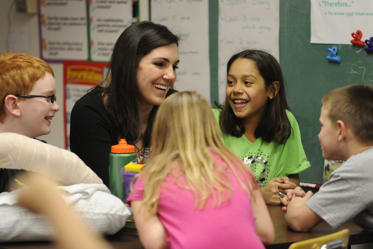 Third-grade teacher Lauren Waterbury chats with students including AJ Dutton, left, and Noraa Christensen, in the green shirt, at Otis Orchards Elementary. (Jesse Tinsley)