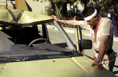 
An injured Iraqi National Guardsman leans on a damaged car after a car bomb exploded as his patrol was passing by in Mosul Monday. 
 (Associated Press / The Spokesman-Review)