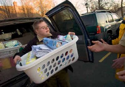 
Boy Scout Chris Naccarato helps deliver baskets of donated items to Anna Odgen Hall women's shelter Wednesday. Naccarato, who has Down syndrome, collected donations outside Fred Meyer in Spokane Valley with the help of fellow Scouts. The effort will help Naccarato earn his Eagle badge. 
 (Colin Mulvany / The Spokesman-Review)