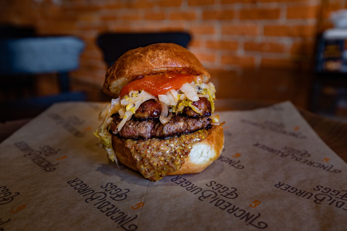 The Bratwurst Burger – an Incredipatty, bratwurst, house sauerkraut, beer mustard and curry ketchup on a pretzel bun – is available this month at Incrediburger and Eggs in downtown Spokane.  (Doyle Wheeler for Eat Good Group)